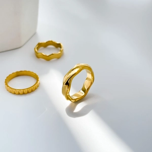 Detailed view of three 18K gold plated steel rings with wave and lava textures