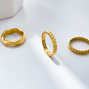 Detailed view of 18K gold plated rings with wave, gear, and striped textured surfaces