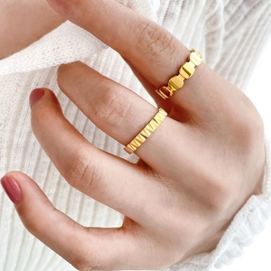 Close-up of two 18K gold plated titanium rings with fish scale and gear textures