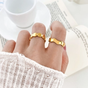 Detail of 18K gold plated titanium rings with wavy and geometric patterns worn on fingers