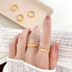 Detailed view of 18K gold plated titanium steel rings with textured fish scale wave patterns