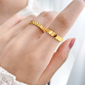 Detail of 18K gold-plated titanium steel rings with textured geometric scale and wave design
