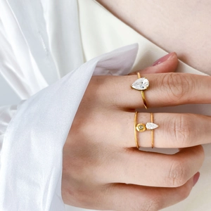 Détail de bagues en titane plaqué or 18K avec zircon en forme de poire sur une main