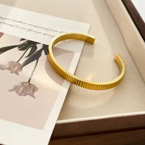 Macro detail of gold ribbed cuff bracelet showing vertical texture and modern C-shape design