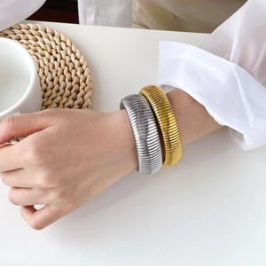 Detail of stacked gold and silver chunky textured cuff bracelets with spring pattern