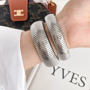 Close-up of wide silver Tubogas spring bracelet with industrial grooved texture