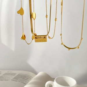 Detail of layered gold snake chains with Faith engraved plaque and heart pendant