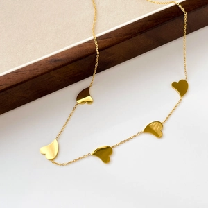 Detail of a gold snake chain necklace featuring five polished heart-shaped pendants