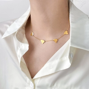 Elegant gold snake chain necklace with five polished heart pendants worn by a model