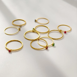 Colorful gemstone ring set in gold plated metal with textured bands on white background