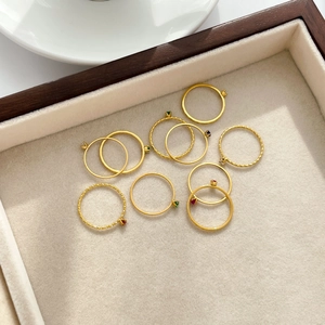Close-up of a multi-piece golden thin ring set with tiny colorful gems on a velvet tray