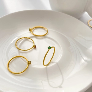 Detailed macro of four minimalist gold textured rings with colorful mini gemstones