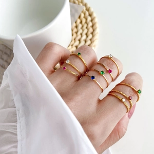 Stackable gold rings set with colorful zircons and twisted bands on hand