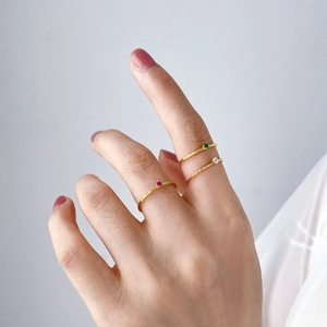 Close-up of three thin gold hammered rings with colorful miniature gemstones on a hand