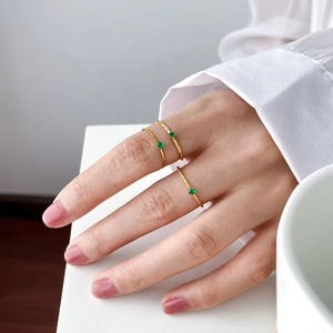 Close-up of minimalist gold stackable rings featuring small green gemstone accents