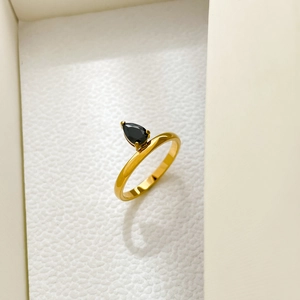 Macro detail of pear-shaped black zircon stone set in gold ring on jewelry box