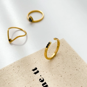 Detailed view of minimalist gold plated rings featuring black pear-shaped zircon stones