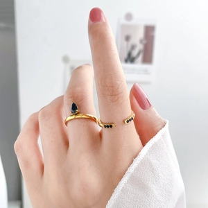 Close-up of golden stackable rings featuring black teardrop zircon and pavé crystals
