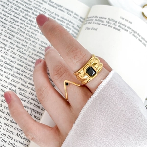 Close-up of a wide gold ring set with a rectangular black zircon on a vintage book