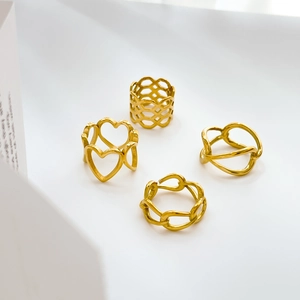 Lot de quatre bagues évidées dorées avec motifs de cœur et de chaîne sur fond blanc