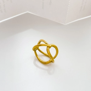 Vue macro d'une bague dorée ajourée avec finition polie sur une surface blanche