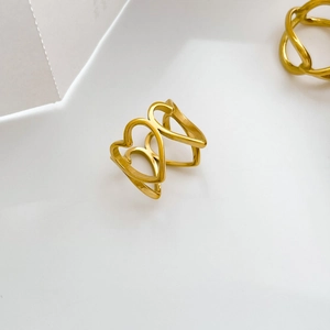 Détail macro de la bague coeur dorée montrant le design ajouré en dentelle complexe