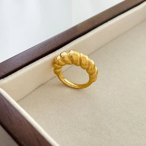 Macro detail of gold chunky croissant ring on velvet jewelry display tray