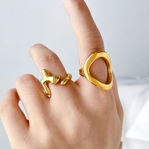 Close-up of hand wearing abstract fluid lava and geometric hollow gold-tone rings