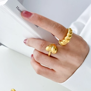 Detailed view of gold plated heart ring and thick twisted croissant ring set on a model