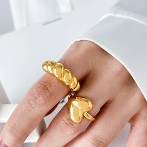 Polished gold lava heart and twisted croissant rings set on model's hand with white shirt