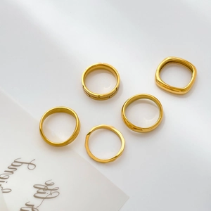 Flat lay of five minimalist 18k gold plated stainless steel rings with geometric textures