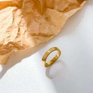 Detailed close-up of a 18k gold plated ring with parallel grooved patterns on a white surface