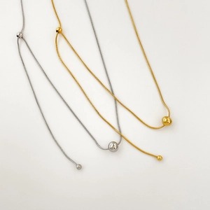 Détail de chaînes serpent minimalistes dorées et argentées avec perles coulissantes fines