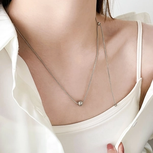 Collier minimaliste en maille serpent argentée avec pendentif sphère polie sur modèle