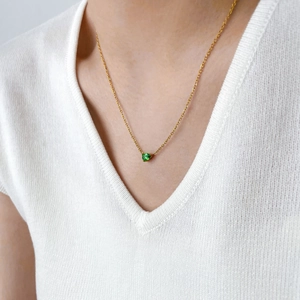 Détail du collier chaîne serpent dorée avec un pendentif en zircon vert en forme de cœur