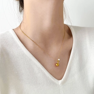 Gros plan d'une fine chaîne serpent dorée avec pendentif goutte et petite perle blanche