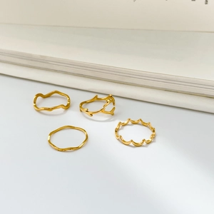 Detailed view of four minimalist gold stackable rings with wave and branch designs