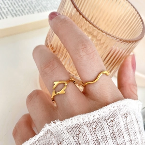 Minimalist gold branch and wave stackable rings shown on model in warm aesthetic lighting