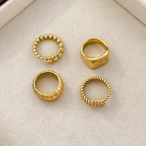 Close-up of four-piece gold stackable rings set including twisted and wave designs