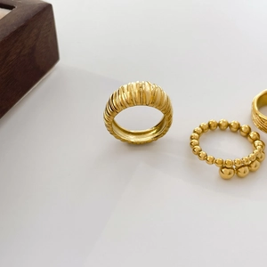Detail of 18K gold-plated wide rippled ring and beaded band set on white background