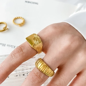 Detail of 18K gold-plated fluid wave ring and ribbed texture ring on model hand