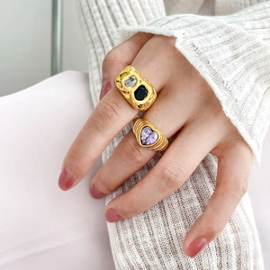 Detail of gold-plated rings featuring heart-shaped purple zircon and black gemstones