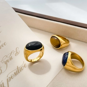 Detailed shot of oval gemstone gold rings in black onyx and blue lapis on beige tray
