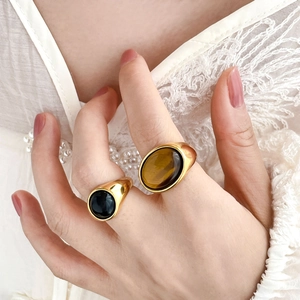 Close-up of gold-plated rings with black onyx and tiger eye stones on a lace background