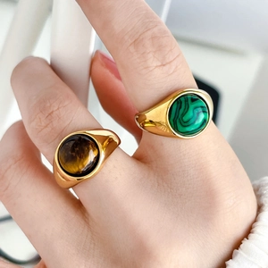 Detailed macro of gold-plated signet rings featuring natural tiger eye and malachite stones