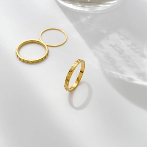 Close-up of golden ring set featuring sunburst texture and beaded edges with water shadows