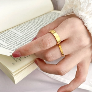 Close-up of vintage gold rings with engraved patterns worn over an open book