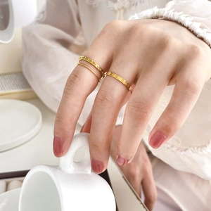 Close-up of three-piece gold textured ring set featuring sunburst and beaded patterns