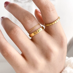 Close-up of three-piece gold ring set featuring Chinese engraving and twisted band