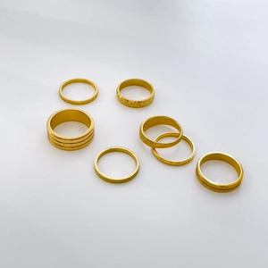 Detail of 7-piece set 18K gold plated titanium rings with matte finish and star carvings
